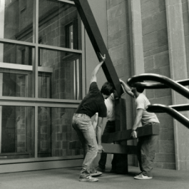Three men moving another large sculpture into the upper atrium of the law school, where it remains today. The sculpture is called "Sedgewick," by artist John Henry.